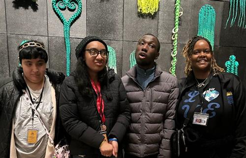  students in front of hair wall with teacher